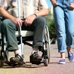 A man in a wheelchair walking next to a young girl