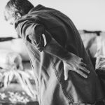 An elderly man hunched over and holding his back
