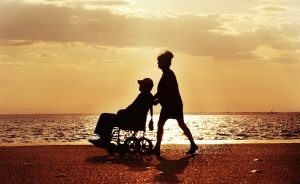 Wheelchair being pushed on a beach  